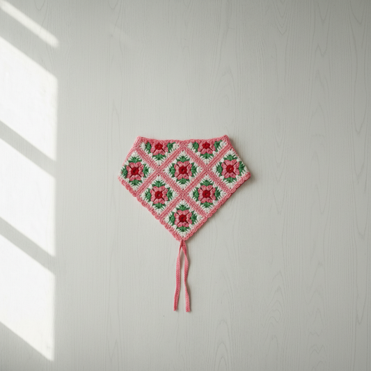 Handmade crochet granny square bandana in pink, red and green on a white background
